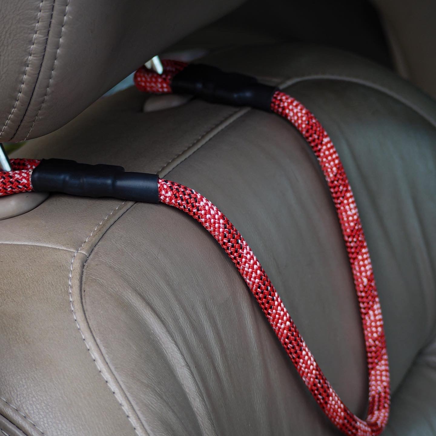 Climbing rope car headrest attachment, looped securely around metal headrest poles inside a vehicle, showcasing a minimalist and functional design.